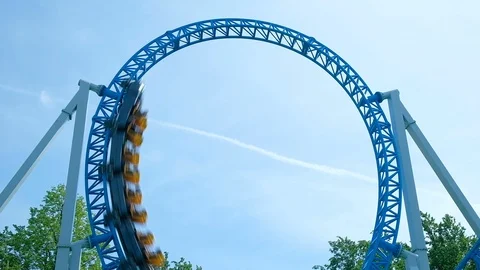 Amusement park visitors ride circle on blue roller coaster Stock Footage