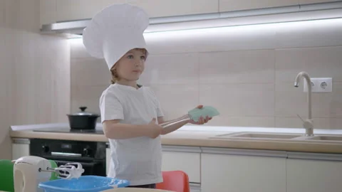 Amusing child wit cook hat have fun in kitchen hold a utensil, sing and dance Vídeos de archivo 138218299