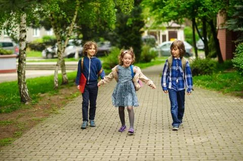 Amusing little school students go to school having joined hands. Stock Photos