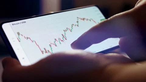 Analizing graph of crypto currency online on smartphone while drinking a cup of Stock Footage 151426857