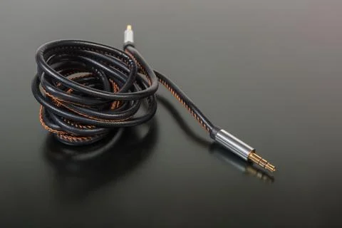 Analog audio cable with mini stereo connectors on dark surface Stock Photos
