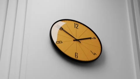 Analog clock with a yellow face hanging on the wall, time goes by Stock Footage 340345740