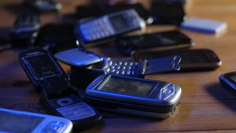 Analog communication. Old broken dusty cell phones lie on table in neon light. Stock Footage 128095593