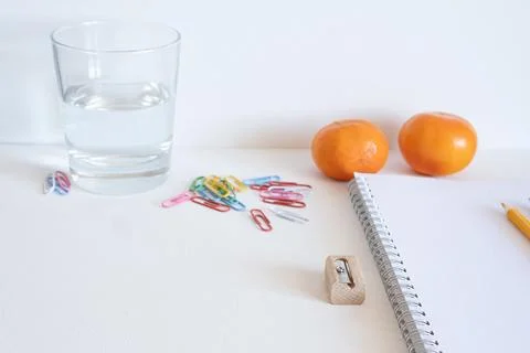 Analog workspace featuring water, assorted paper clips, fruit Stock Photos