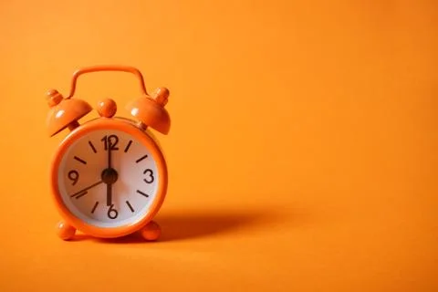 Analogue clock on orange background. Stock Photos