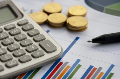 Analysis of data, chart and graphs with calculator, pen and gold coins back.. Stock Photos