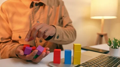 An analyst arranges colorful blocks into stacked layers. Stock Footage 317599578