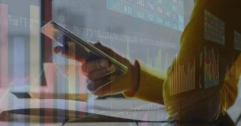 Analyst holding smartphone and viewing laptop screen in office, with notebook Stock Photos