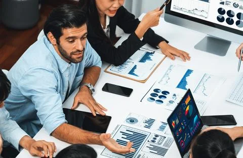 Analyst team utilizing BI Fintech to analyze financial data at table. Prudent Stock Photos