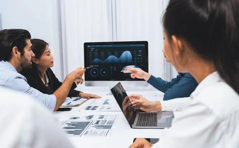 Analyst team utilizing BI Fintech to analyze financial data at table. Prudent Stock Photos