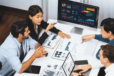 Analyst team utilizing BI Fintech to analyze financial data at table. Prudent Stock Photos