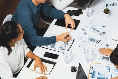 Analyst team utilizing BI Fintech to analyze financial data at table. Prudent Stock Photos