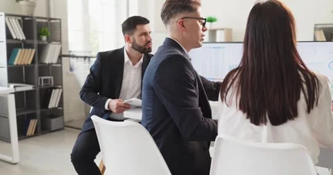 Analysts collaborating at computer screens in office, reviewing finance charts Stock Footage 342081929