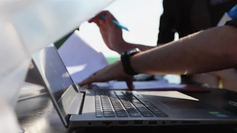 Analysts in the field sit at laptop computer and examine paperwork Stock Footage 302776970