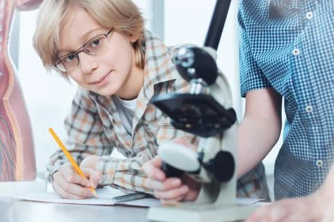 Analytical intelligent kid writing down obtained data Foto stock