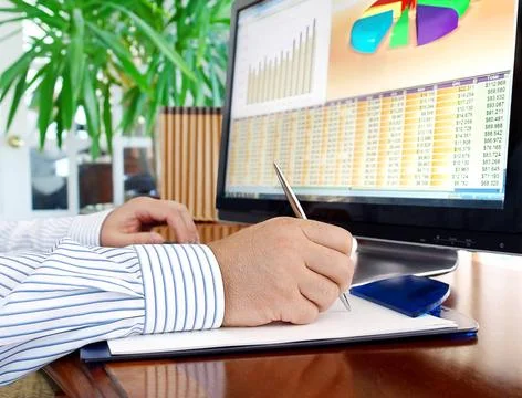 Analyzing data on computer Male hands with pen analyzing financial data an... Stock Photos