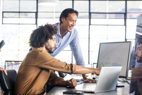 Analyzing data on computer screen, colleagues collaborating on project in office Fotos de archivo