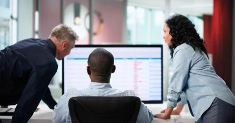 Analyzing Data On Multiple Computer Screens In A Business Office. 写真素材