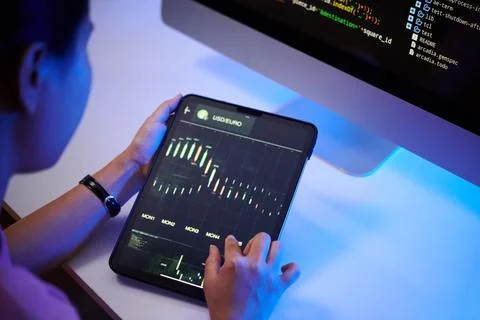 Analyzing Data on Tablet with Code on Monitor in Background Stock Photos