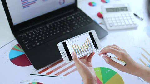 Analyzing financial data with mobile phone and computer Stock Footage 221556615