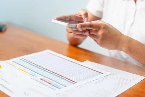 Analyzing financial data a smartphone at a desk home office daily task elev.. Stock Photos