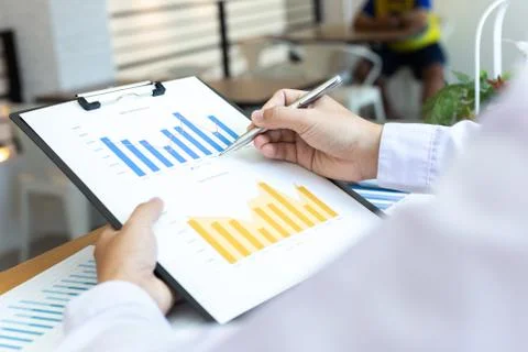 Analyzing graphs, Chai used a pen to point to the graph to analyze the busine Stock Photos