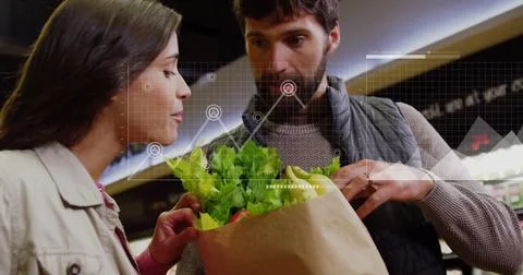 Analyzing grocery shopping data image over couple examining fresh produce in Foto stock