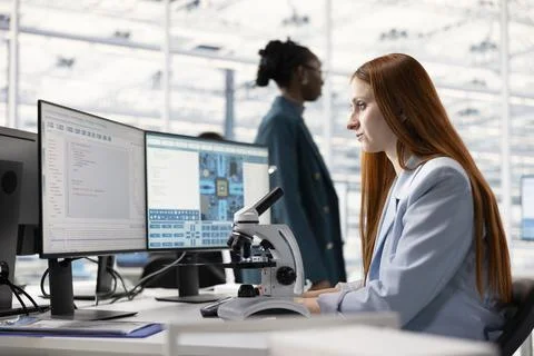 Analyzing integrated circuit, laboratory microscope and woman in RD office Stock Photos