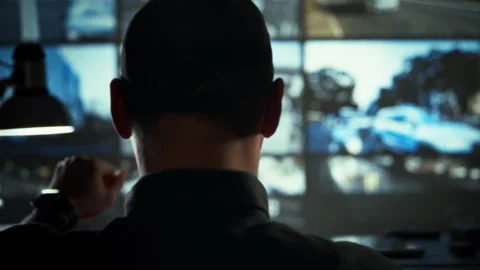 Analyzing live video streams a worker in gear at the monitoring center watch Stock Footage 334545717