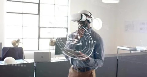 Analyzing man wearing VR headset holding tablet using holographic interface in Stock Photos