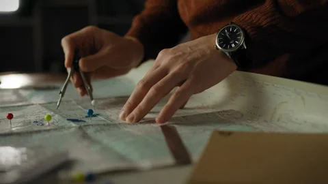 Analyzing a map with precision tools and attention in a dimly lit room Stock Footage 331288913