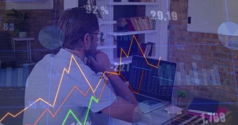 Analyzing middle-aged man using laptop in home office, with financial charts and 库存照片