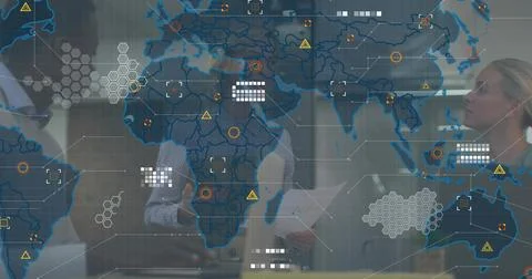 Analyzing team wearing blazers studying data overlays on glass wall in office, Stockfoto's