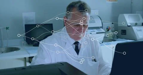 Analyzing technician wearing lab coat and tie focusing on computer screen in Stock Photos