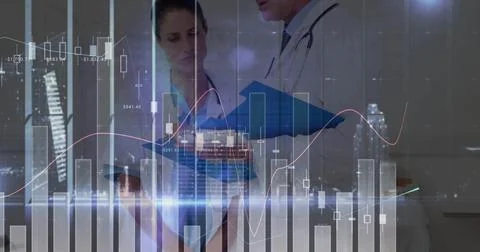Analyzing two doctors in white coats reviewing data on blue tablet in clinic, Foto stock