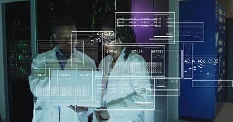 Analyzing two engineers wearing white lab coats examining hologram data in Stock Photos