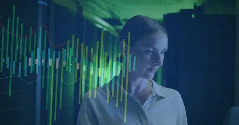 Analyzing woman in button blouse reading data charts at dim office, candlestick Stock Photos