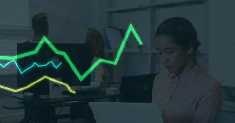 Analyzing woman in patterned blouse using laptop in office with colored graph Stock Photos