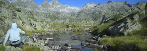 Anamorphic Lens 6K - Sweaty guy relaxes after arriving at a glacial lake Stock Footage 341642772