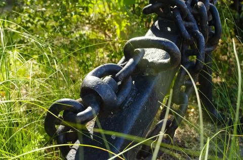 Anchor with a chain in the grass in the rays of the summer sun. The concept o Foto stock