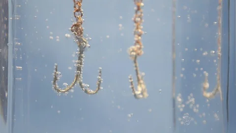 An anchor in the form of two hooks in the water is covered with bubbles Stock Footage 123963166
