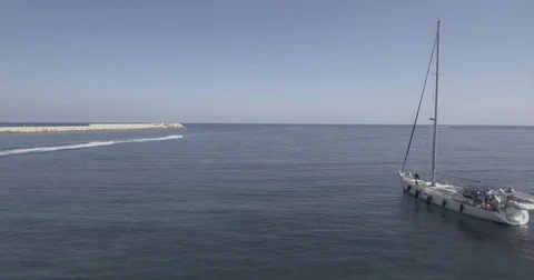 Anchored sail boat is passed by two jet skies Stock Footage 71650322