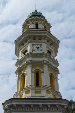 Ancient beautiful tower with a clock with a pointed spire on the top piercing Stock Photos
