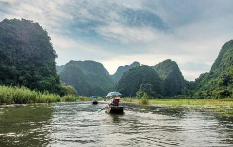 Ancient boating with vietnamese using foot paddle and view limestone mountain Stock Photos