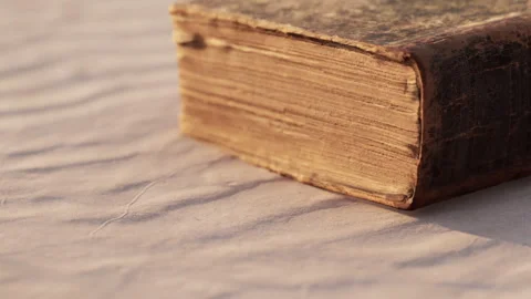 Ancient Book Rests on Soft Fabric, Revealing Its Weathered Pages and History Stock Footage 344910109