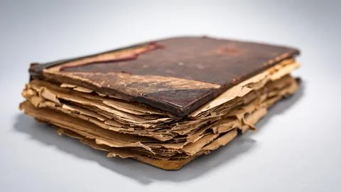 Ancient book with worn pages and faded cover resting on a neutral surface Stock Photos