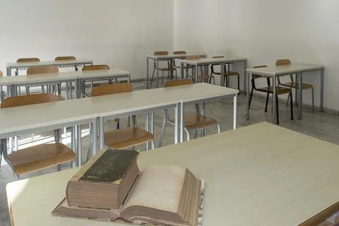 Ancient books open on desk in empty modern classroom Stock Photos