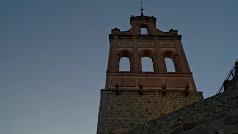 Ancient brick bell tower rising from stone city walls against a clear blue .. Stock Footage 335640021