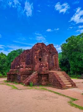 Ancient brick structure stands among green trees under a blue sky in a hist.. Stock Photos