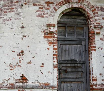An ancient brick wall with a door made of old wood. An old wooden door in an old Stock Photos